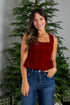 Woman wearing a red top and blue jeans standing in front of a decorated Christmas tree.