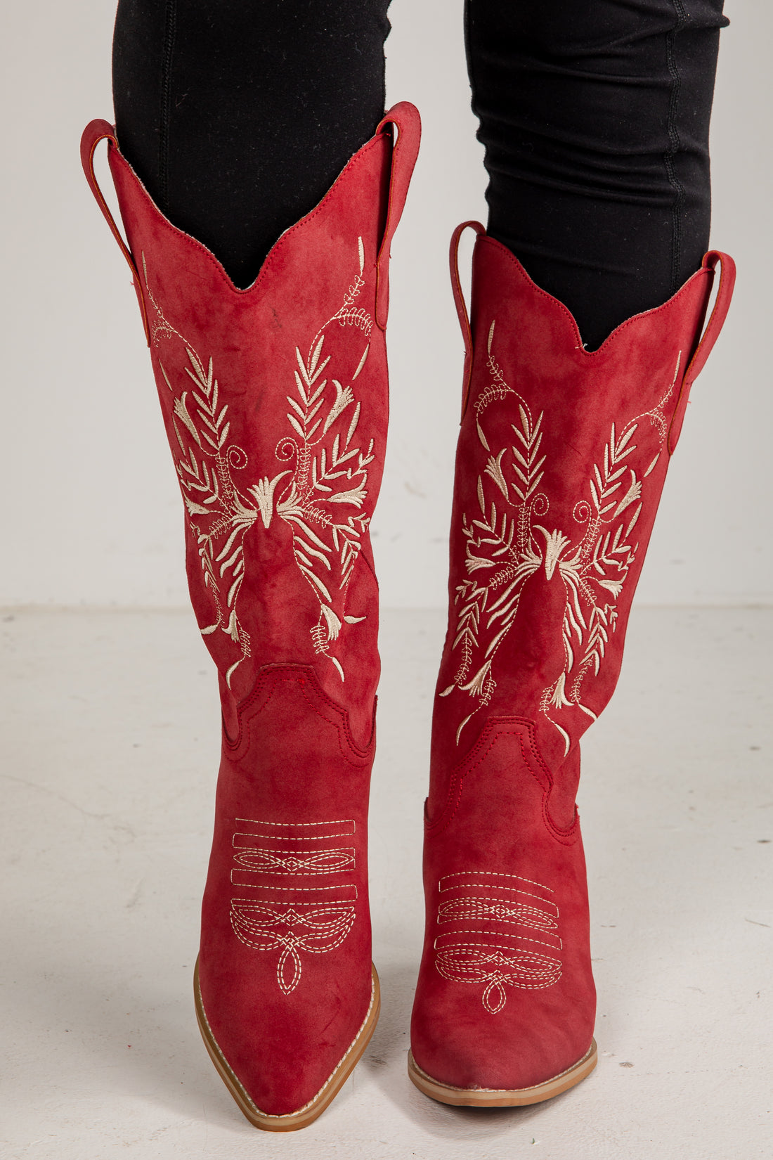 Red cowboy boots with white embroidery on a white background