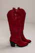 A pair of red leather cowboy boots with embossed western stitching, silver-tone studs, and black block heels, photographed against a plain off-white background.