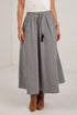 A woman wearing a black and white micro-checkered midi skirt with a drawstring waist, paired with a white top and brown suede ankle boots.