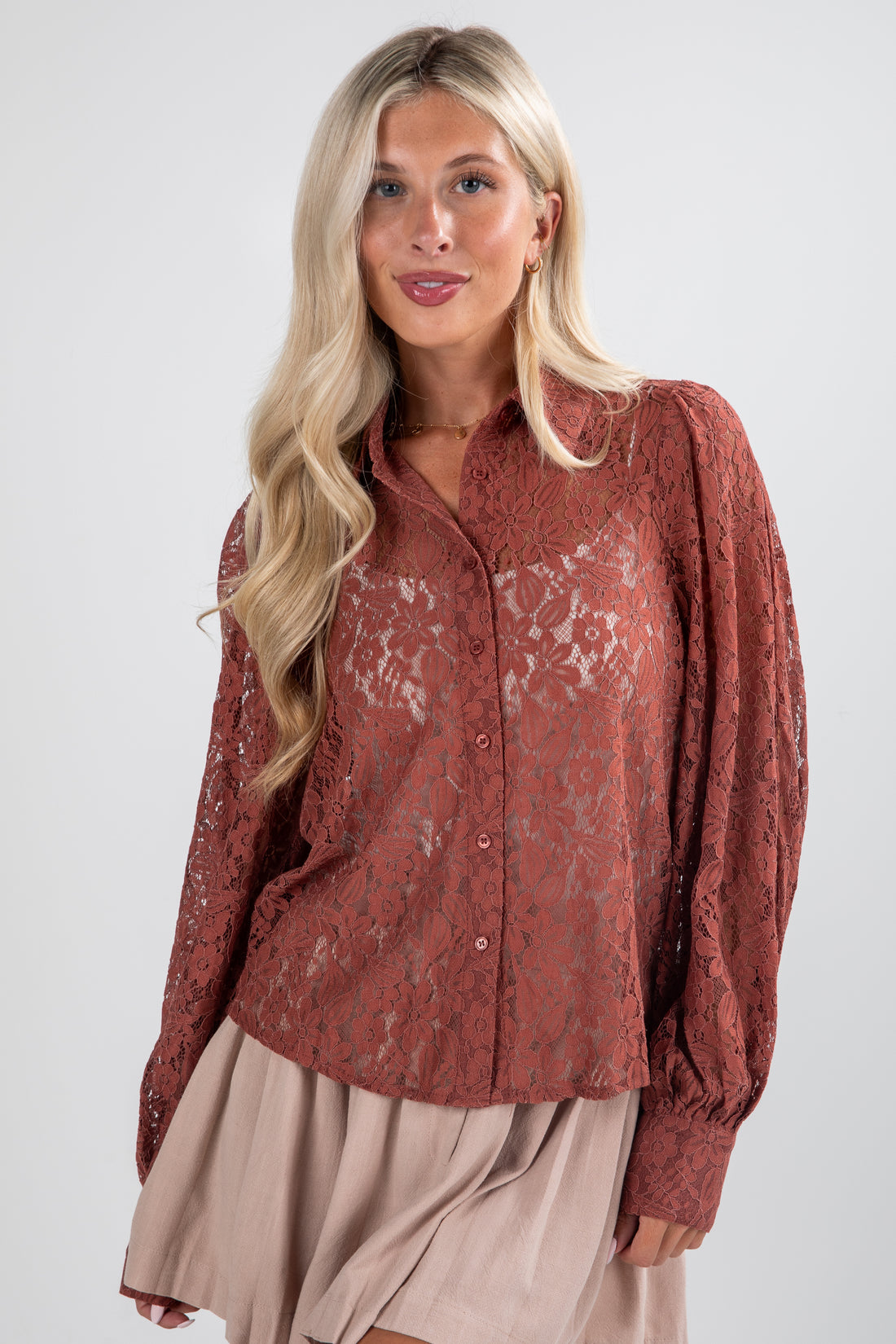 Woman wearing a rust-colored lace blouse against a white background