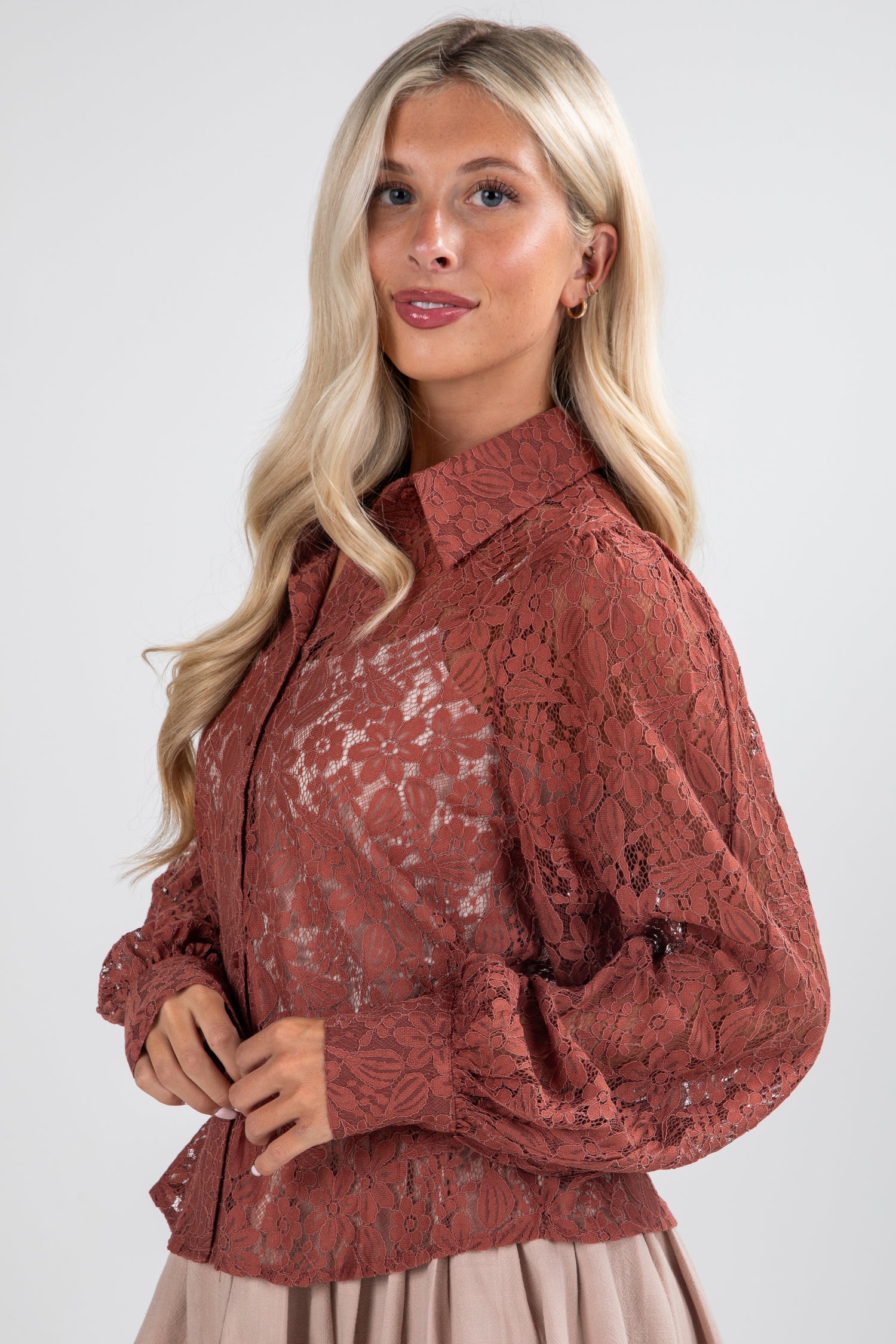 Woman wearing a rust-colored lace blouse against a white background