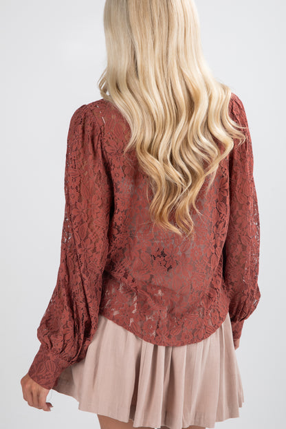 Person wearing a red lace top and beige skirt on a white background