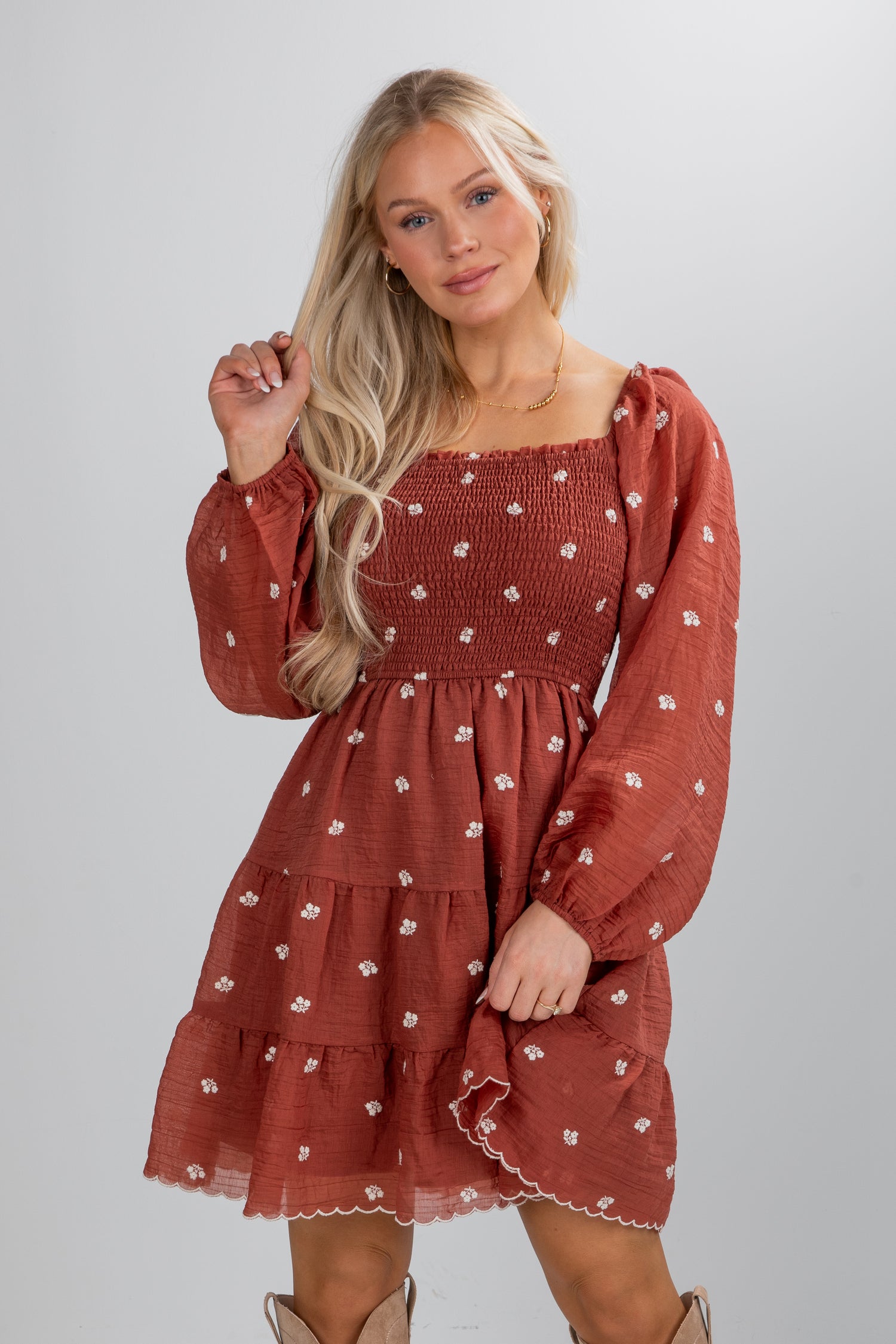 Woman wearing a rust-colored dress with floral pattern on a white background