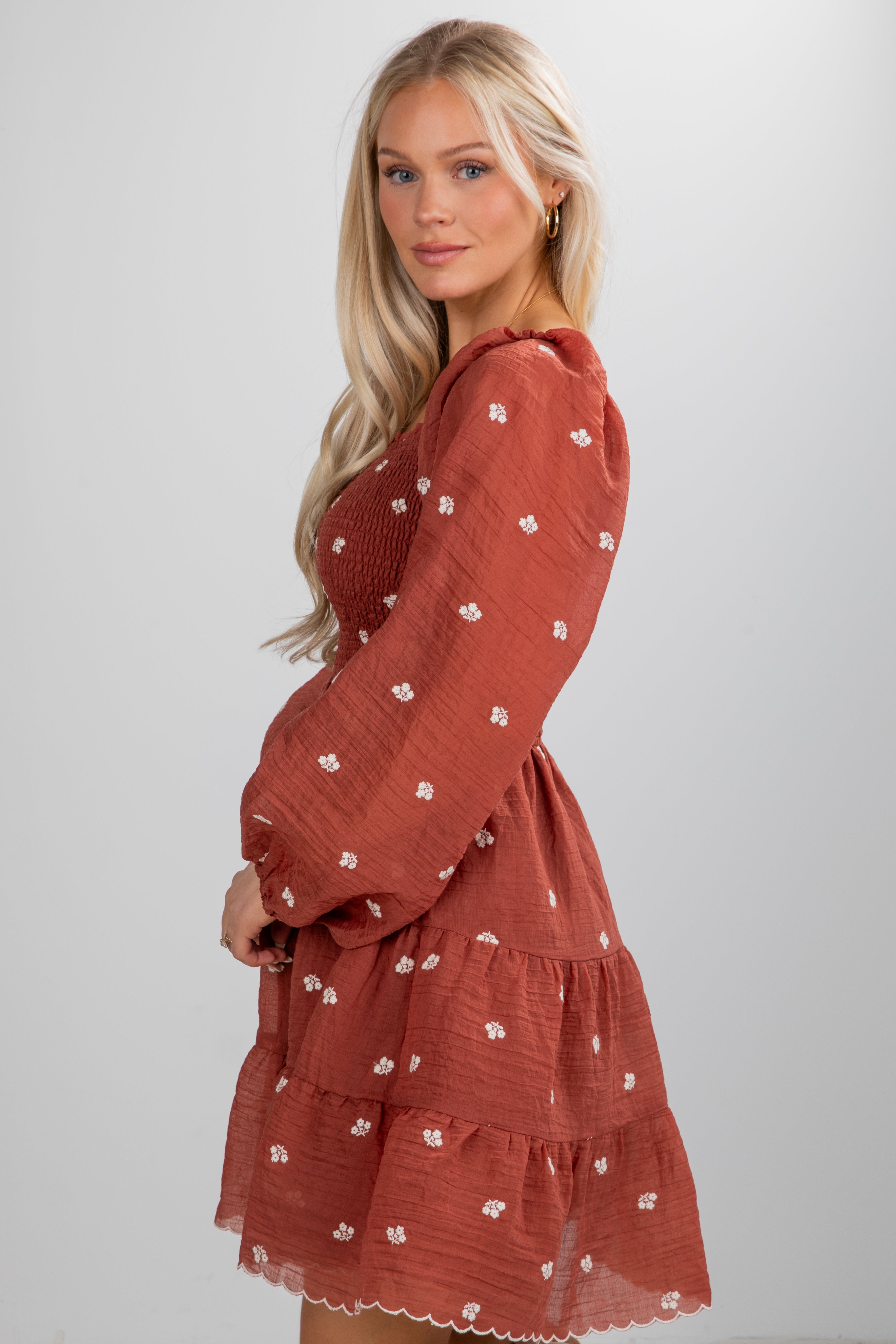 Woman wearing a rust-colored dress with floral pattern on a white background