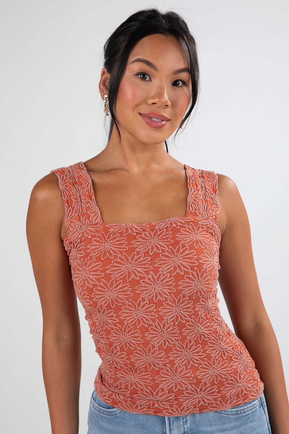 Woman wearing a patterned orange tank top against a white background