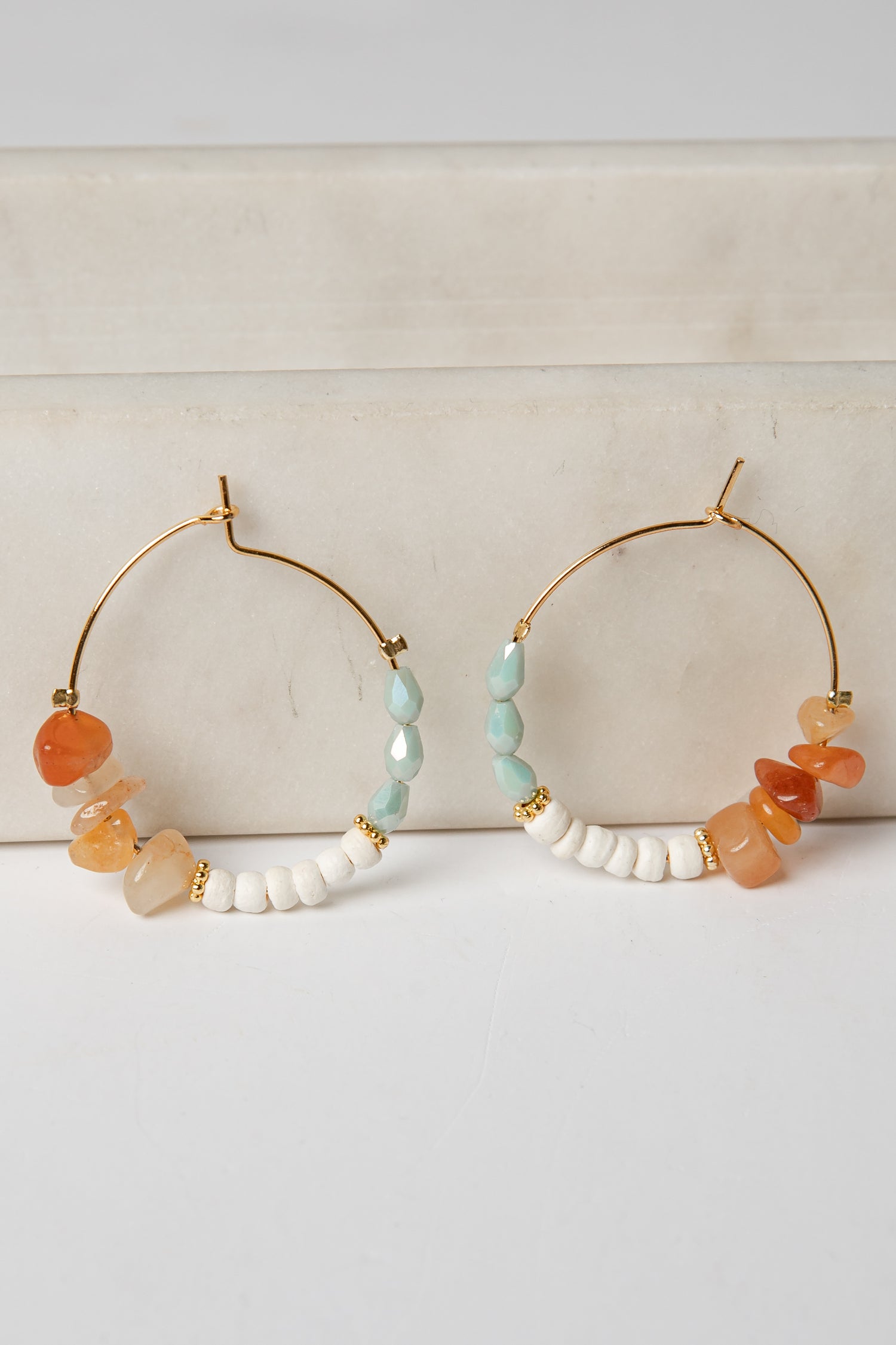 Pair of hoop earrings with colorful beads on a light background