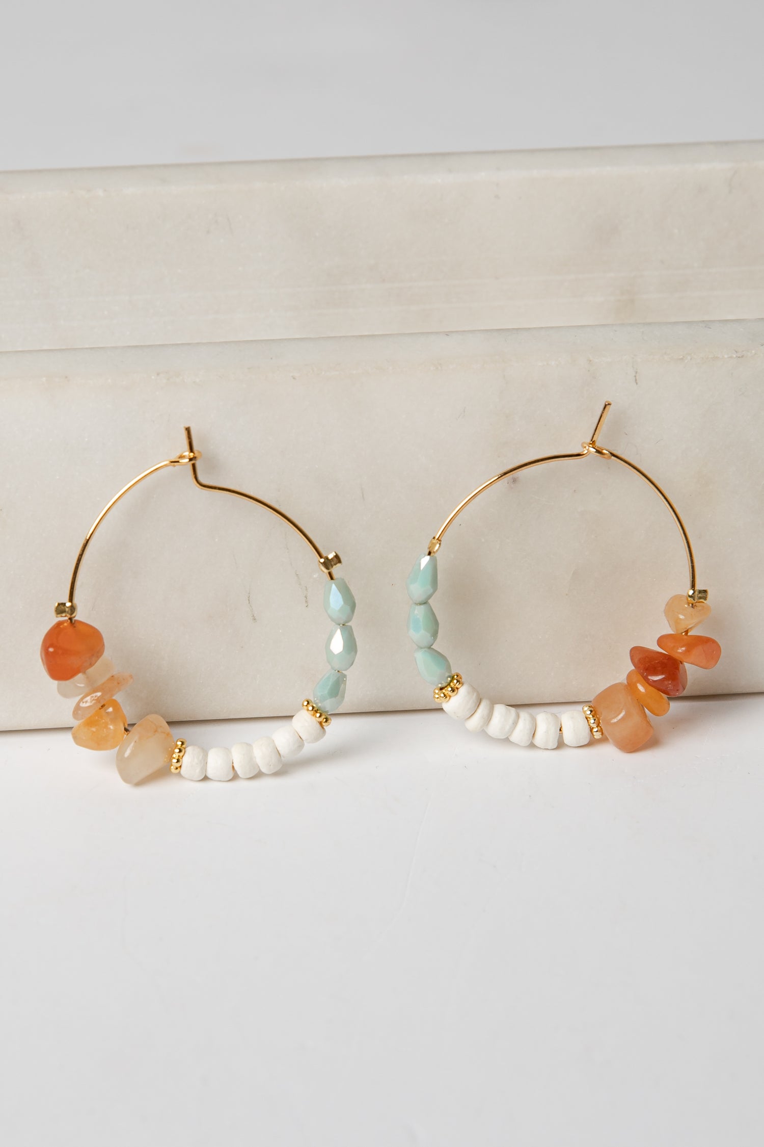 Pair of hoop earrings with colorful beads on a light background