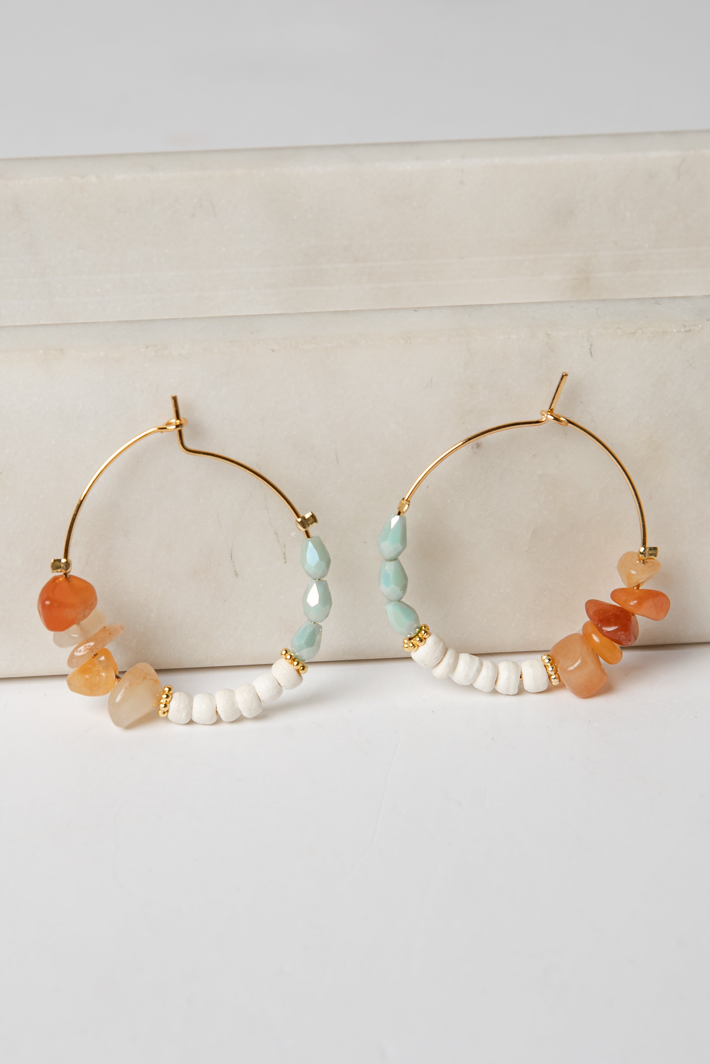 Pair of hoop earrings with colorful beads on a light background