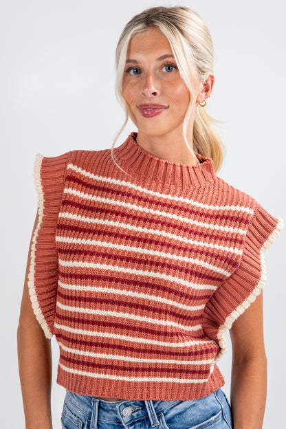 Woman wearing a rust-colored striped sweater vest against a white background