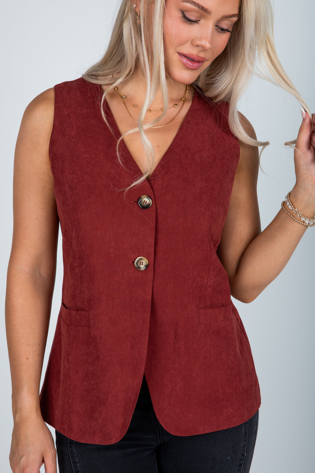 Woman wearing a red vest with buttons on a plain background