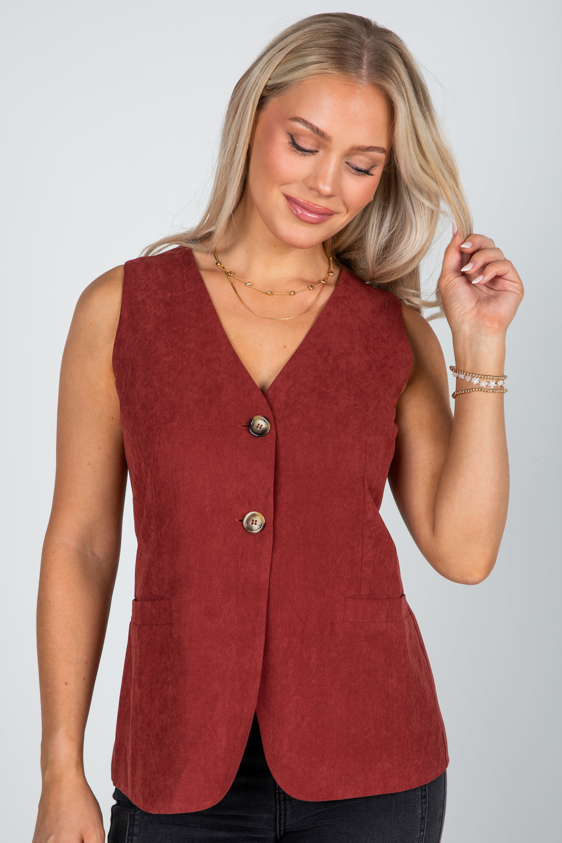 Woman wearing a red vest with buttons on a plain background