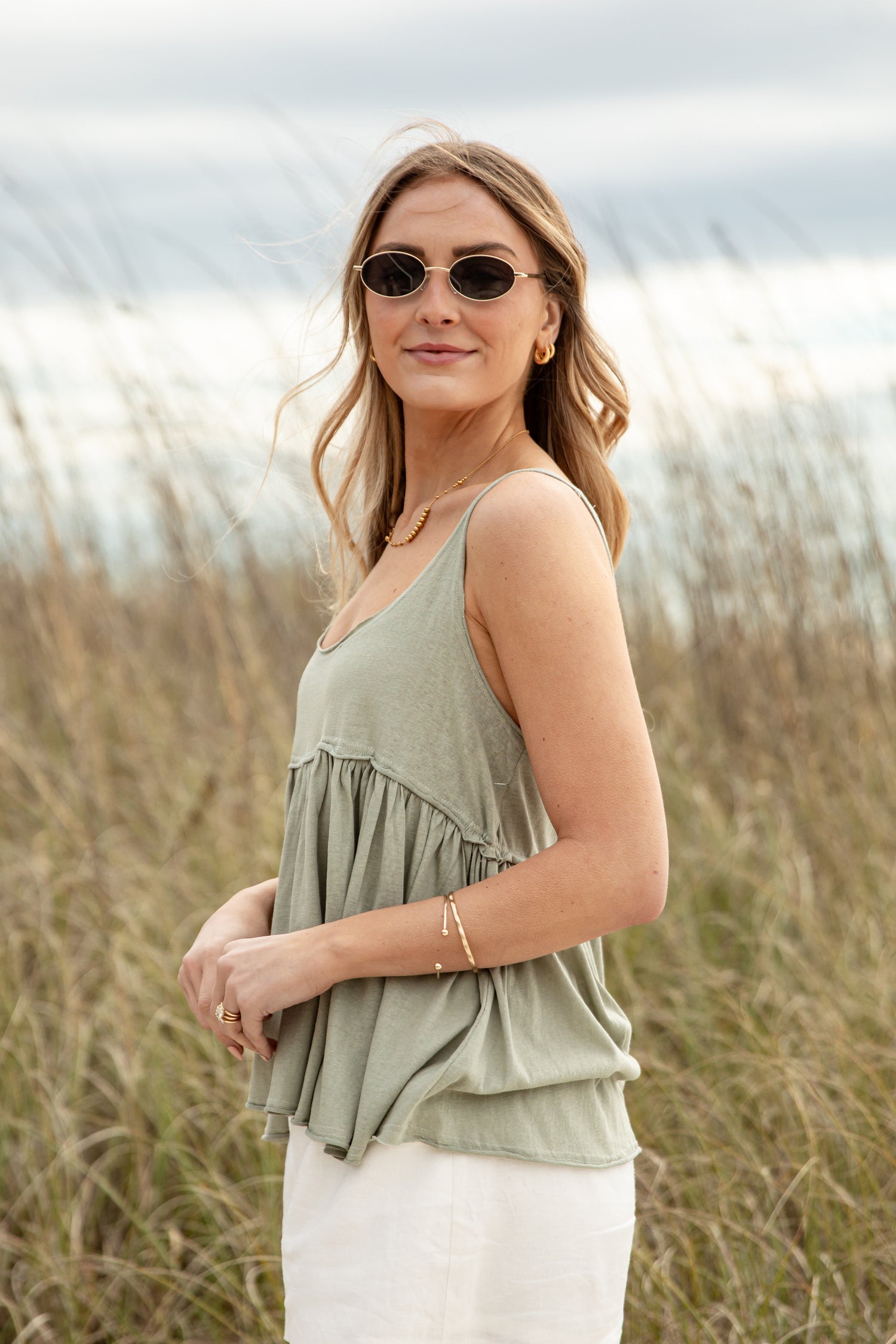 Woman wearing a green sleeveless top and sunglasses in a field