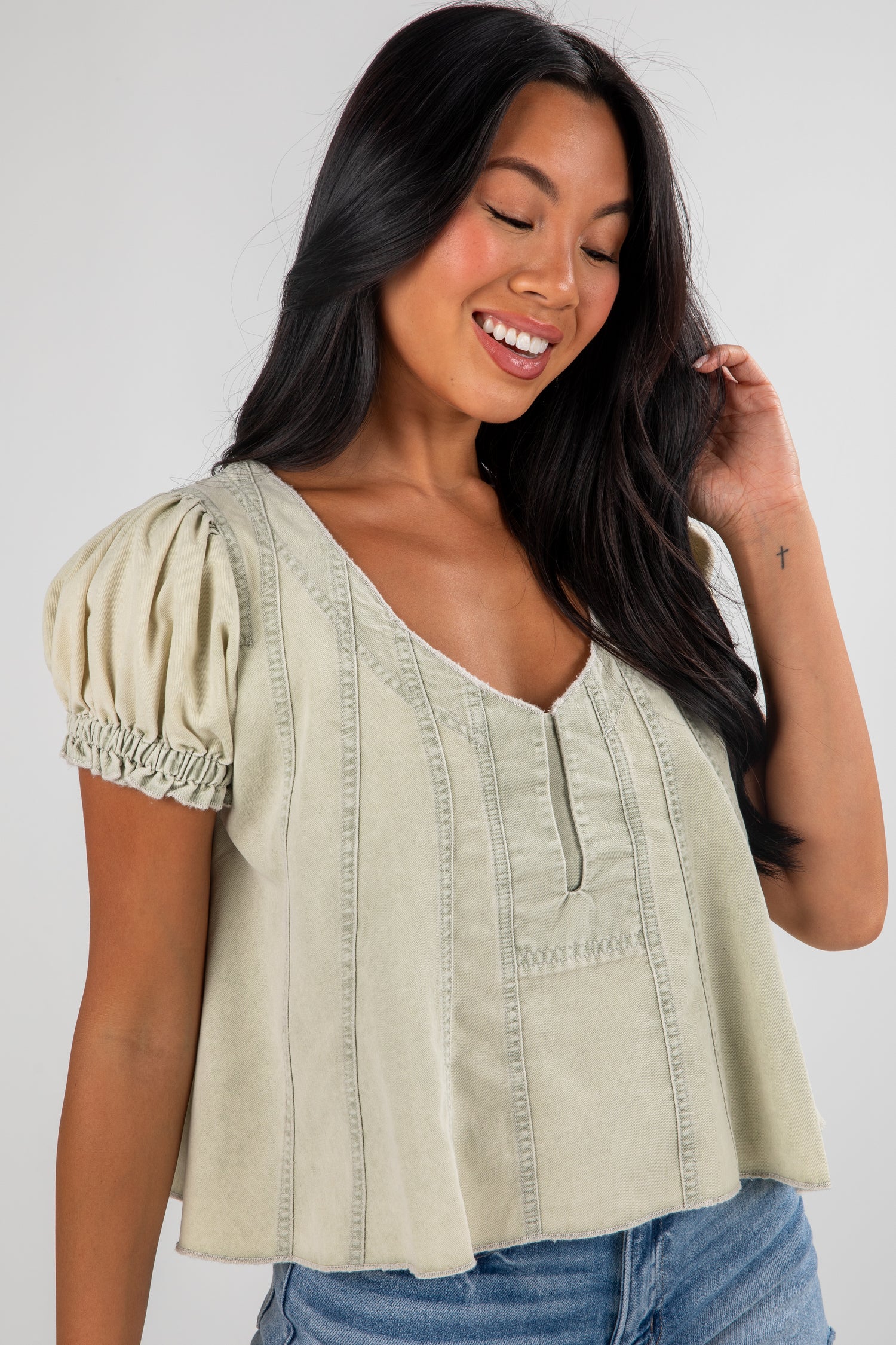Woman wearing a light green blouse with puff sleeves against a white background
