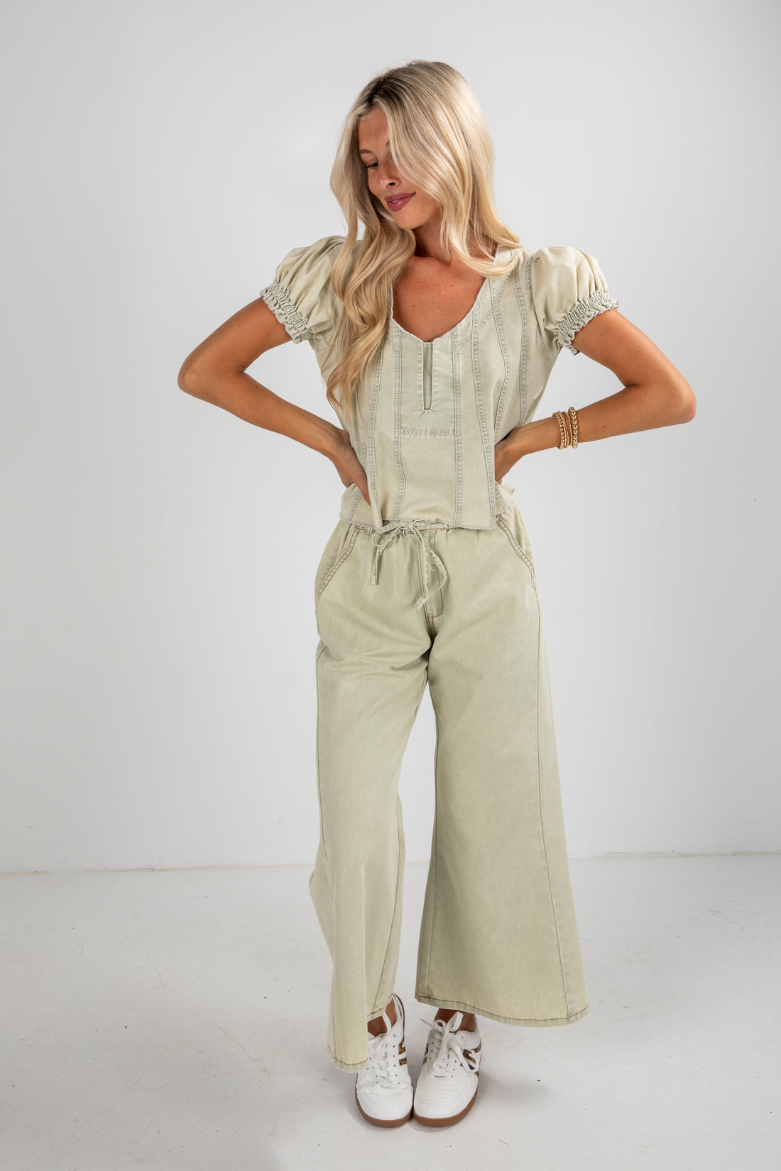 Woman wearing a light green outfit with wide-leg pants on a white background