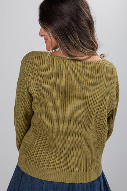 Woman wearing a green knitted sweater against a plain background