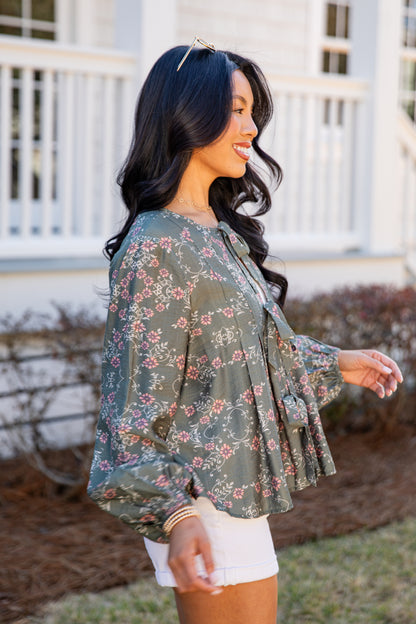 Woman wearing a floral blouse outdoors with a blurred background