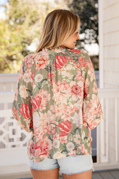 Woman wearing a floral blouse with a blurred outdoor background
