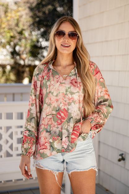Woman wearing a floral blouse and denim shorts outdoors.