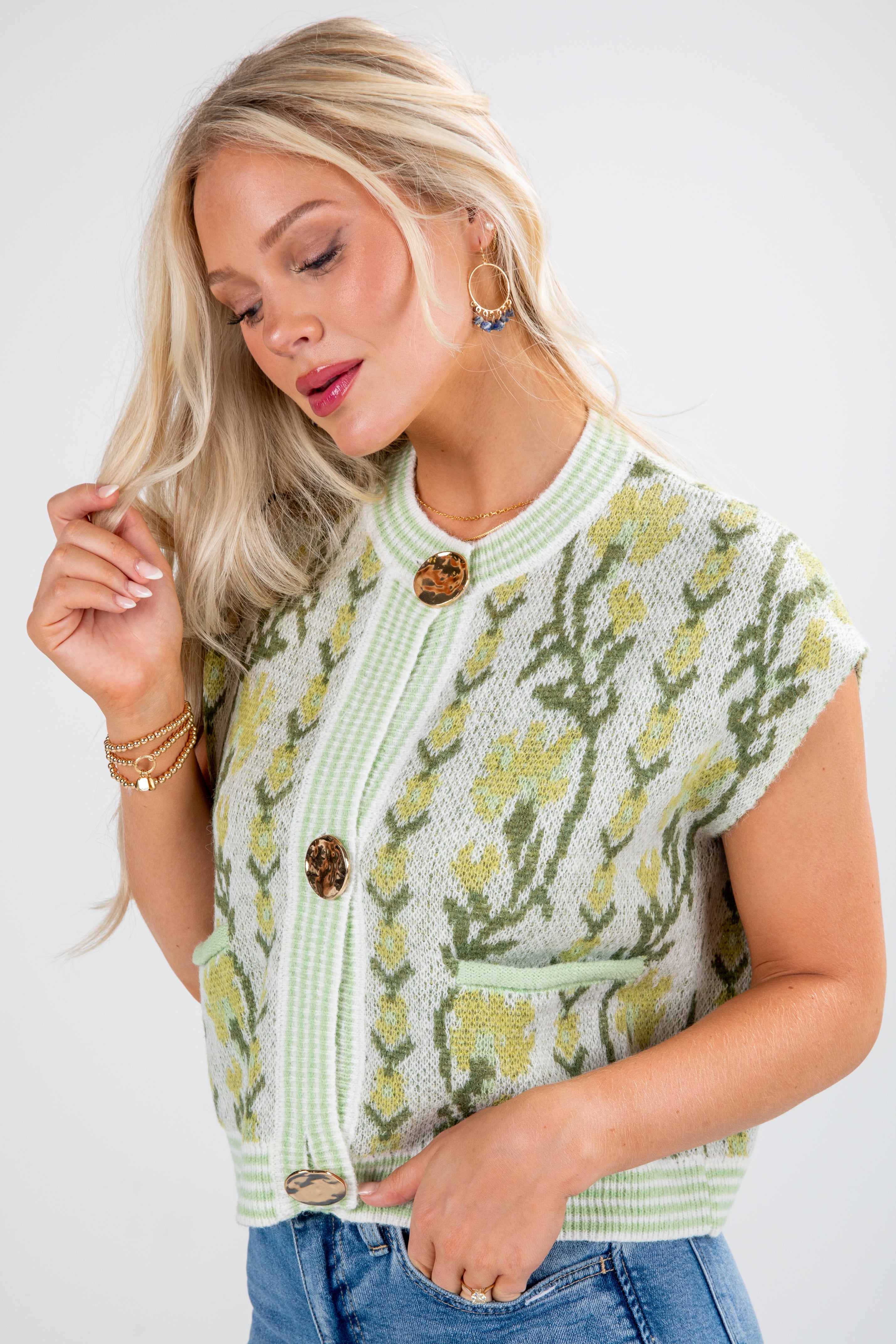 Woman wearing a light green cardigan with floral patterns on a white background