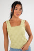 Woman wearing a light green sleeveless top against a white background