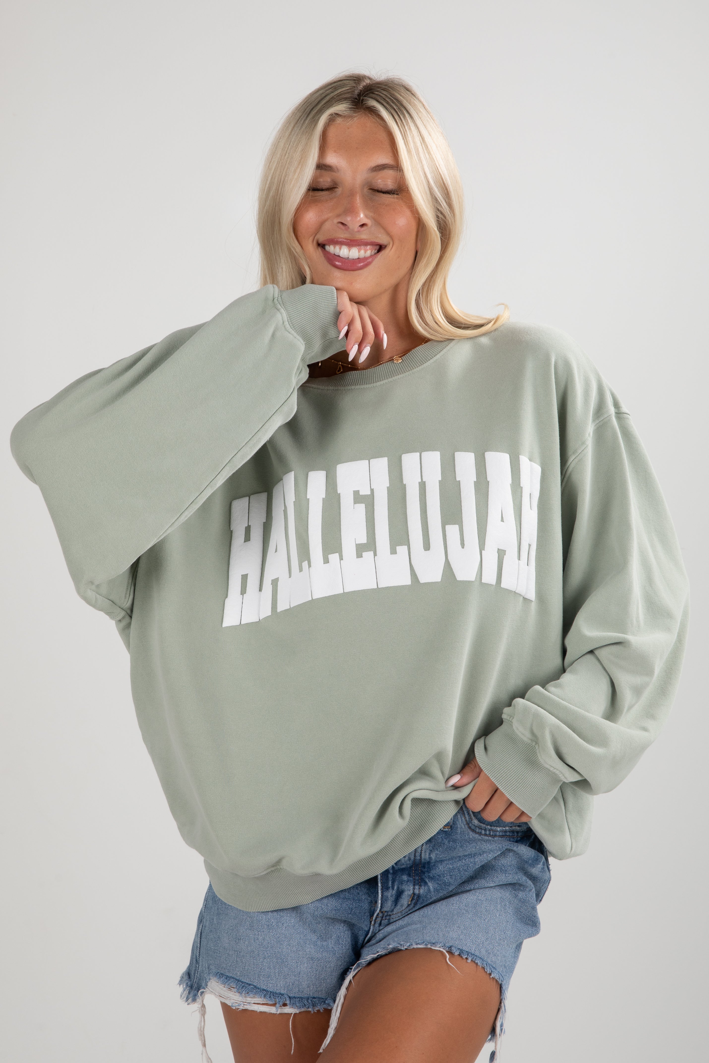 Woman wearing a light green sweatshirt with &