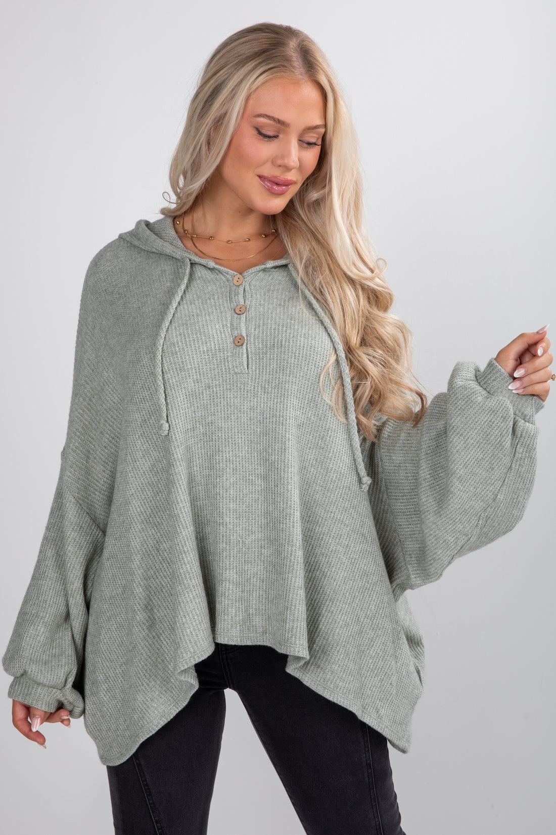 Woman wearing a green hooded sweater against a white background