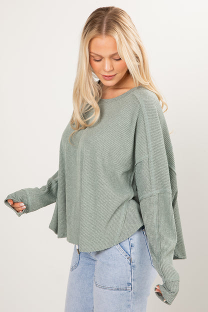 Woman wearing a green sweater and light blue jeans on a white background