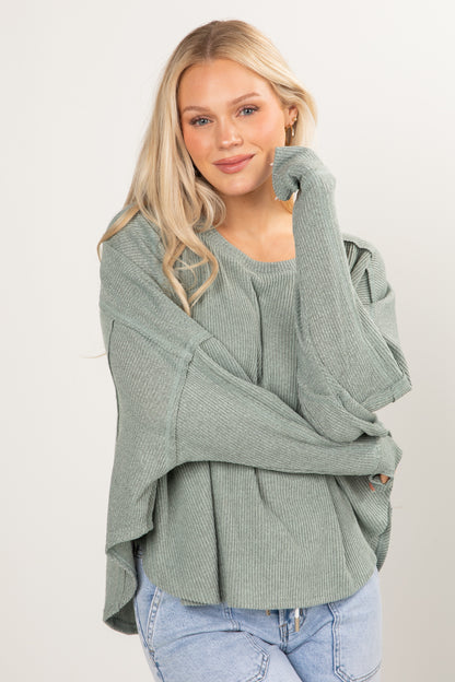 Woman wearing a green knitted sweater with a white background