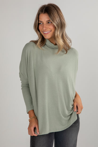 Woman wearing a green long-sleeve top against a plain background