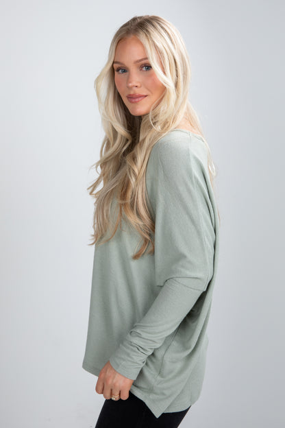 Woman wearing a light green long-sleeve top against a plain background