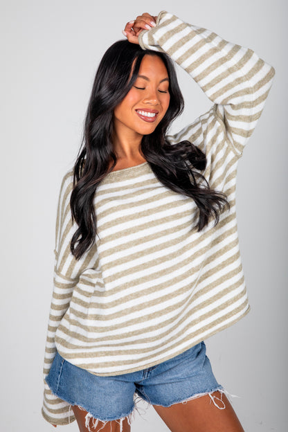Woman wearing a striped long-sleeve top and denim shorts against a plain background