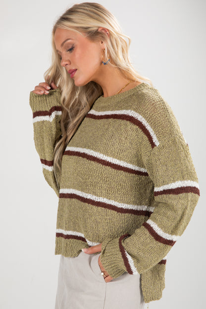 Woman wearing a green sweater with brown and white stripes on a white background