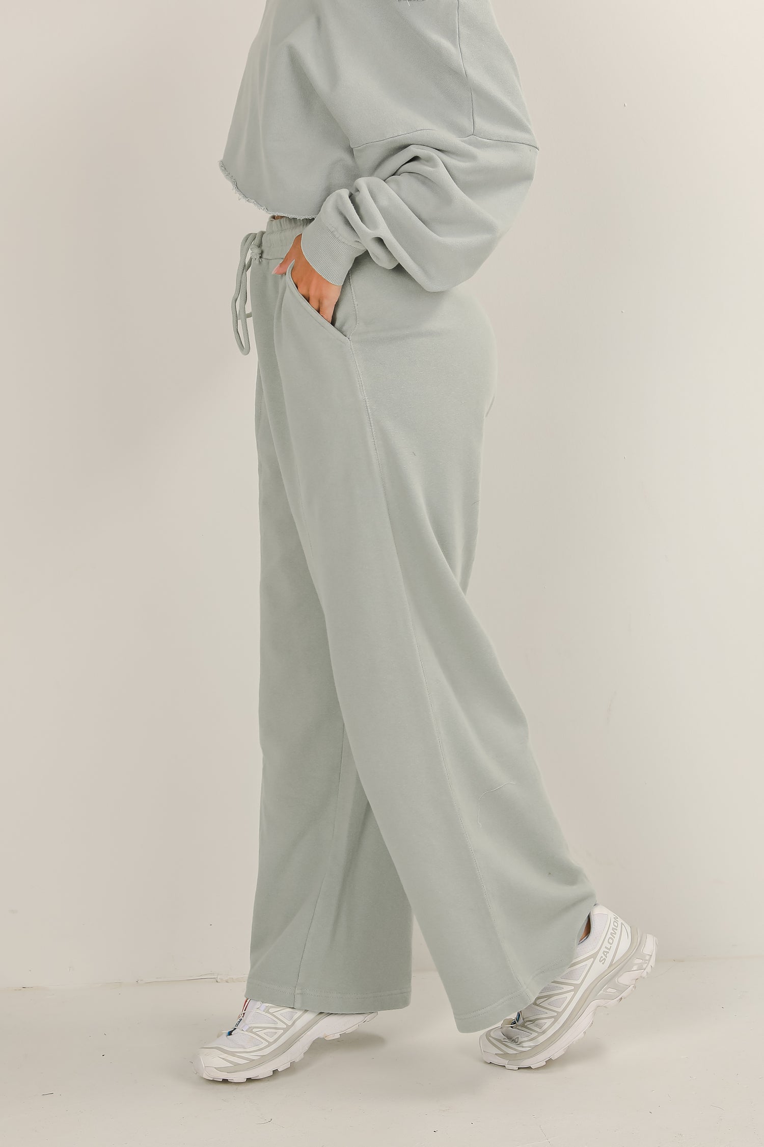 Person wearing a light gray outfit with wide-leg pants on a plain background