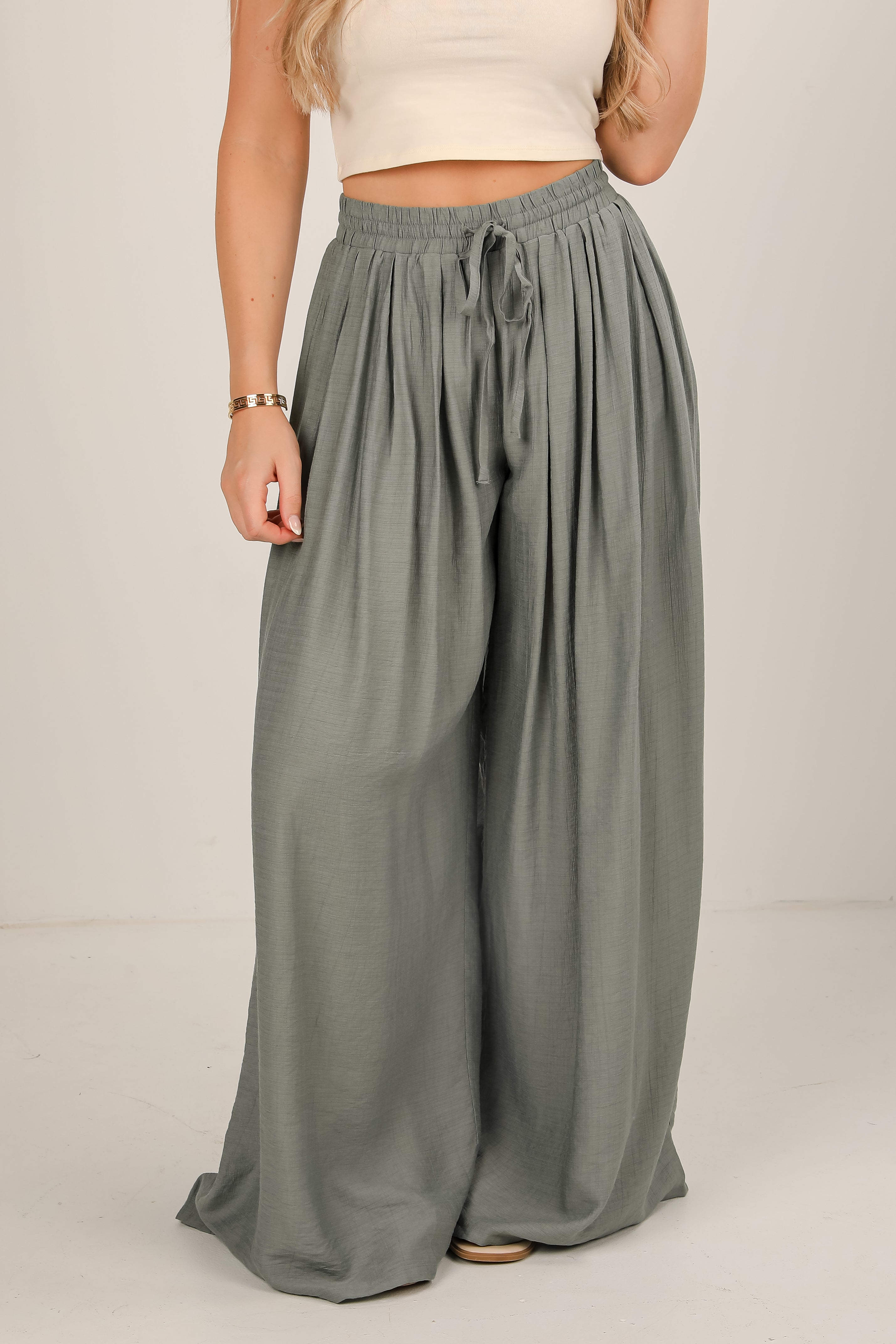 Person wearing olive green wide-leg pants on a plain background