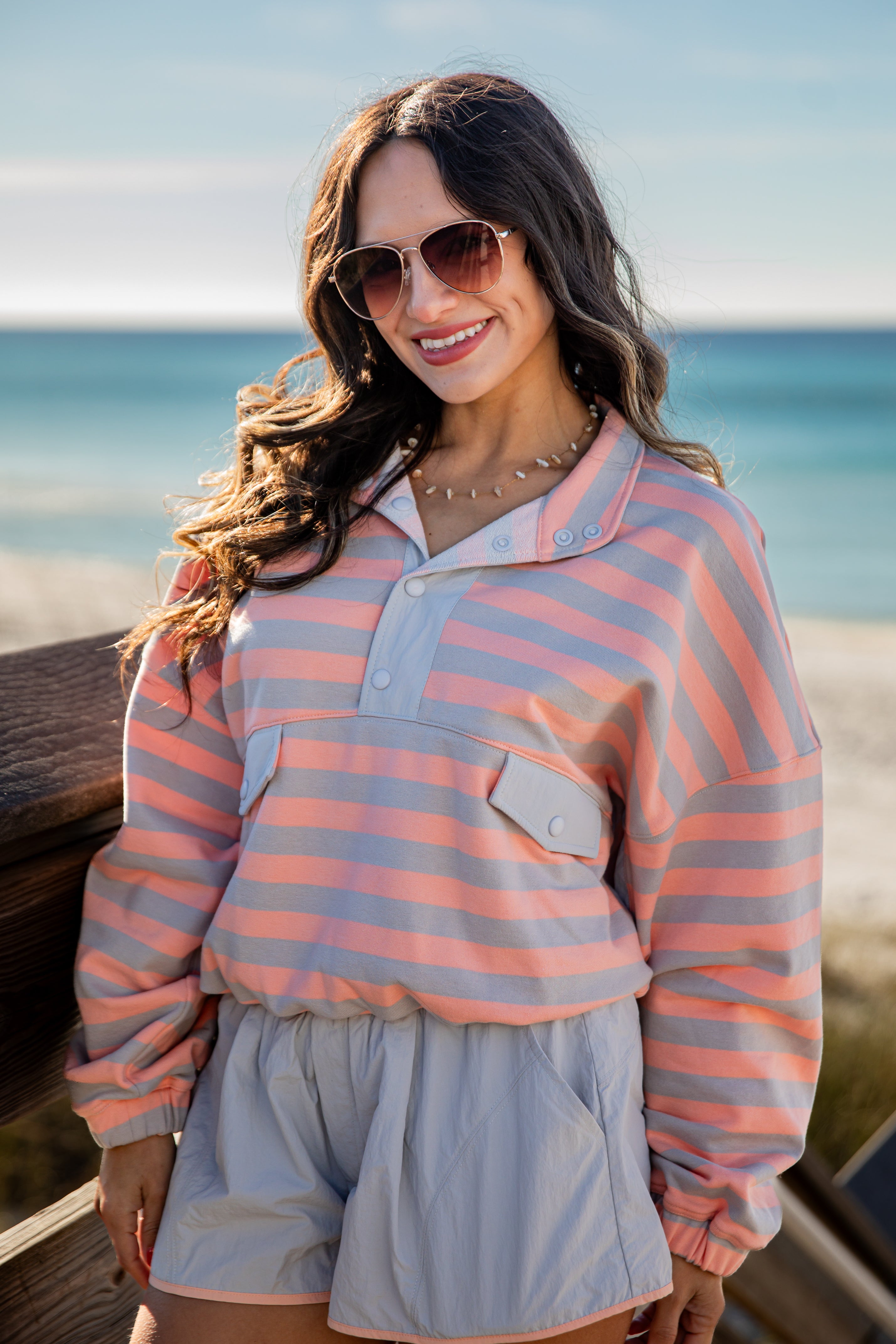 Woman wearing a striped shirt and sunglasses by the ocean