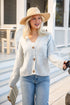 Woman wearing a light blue cardigan, jeans, and a straw hat outdoors.