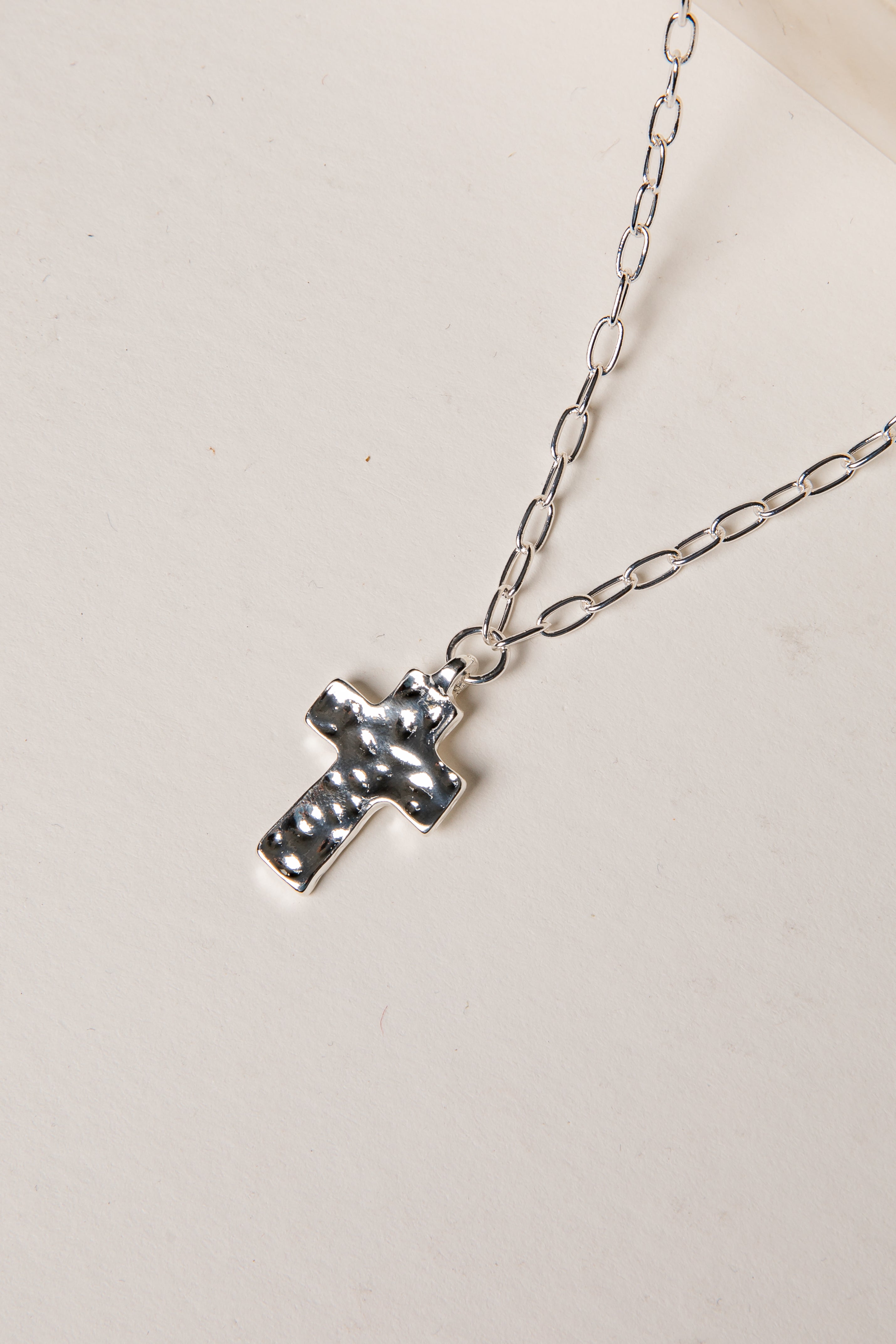 Silver cross necklace on a light background