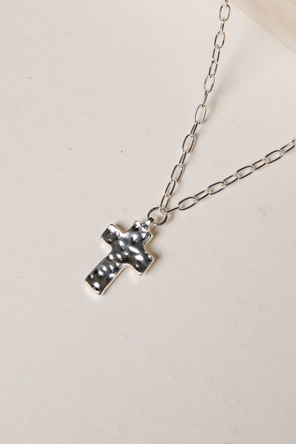 Silver cross necklace on a light background