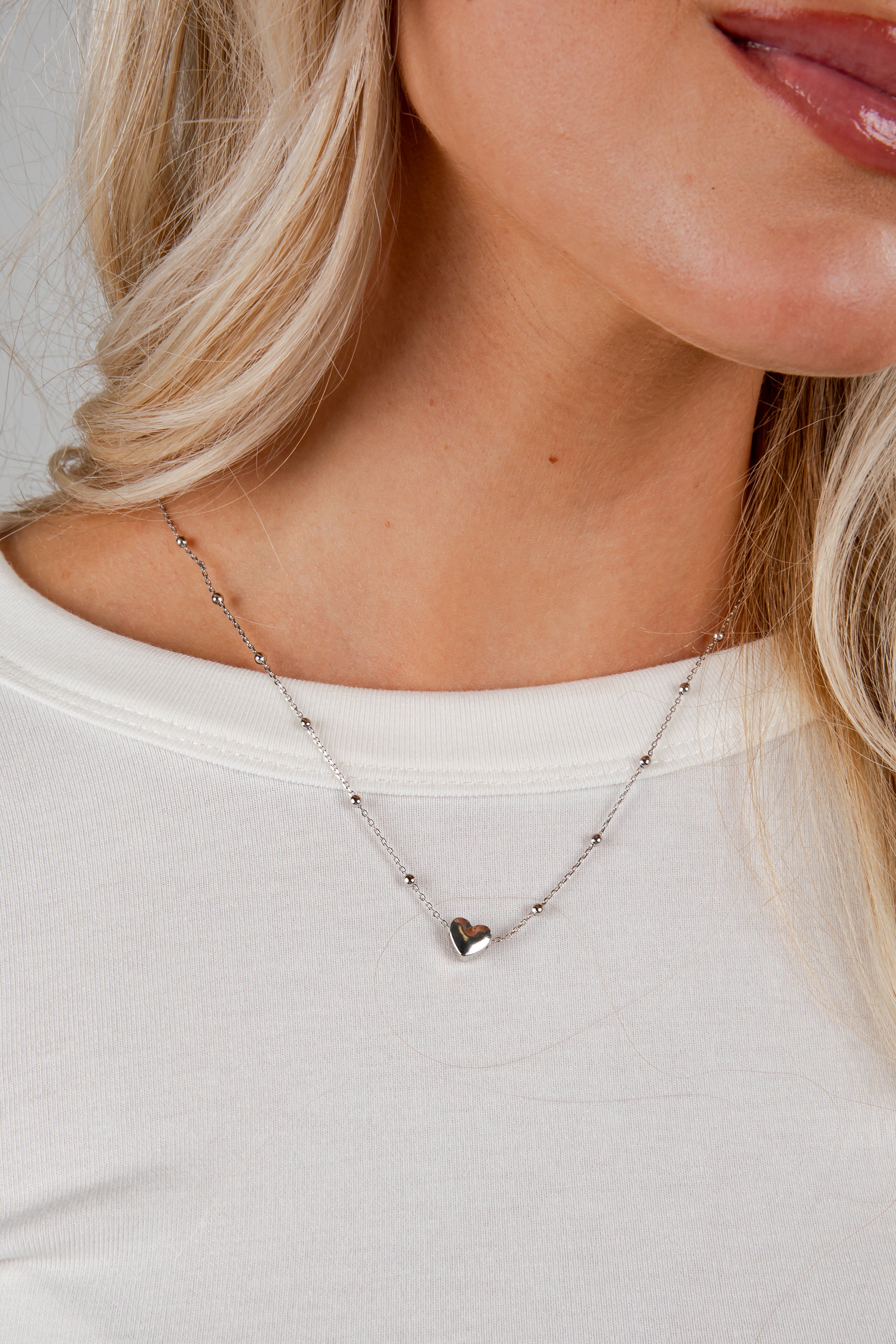 Close-up of a necklace with a heart pendant worn by a person.