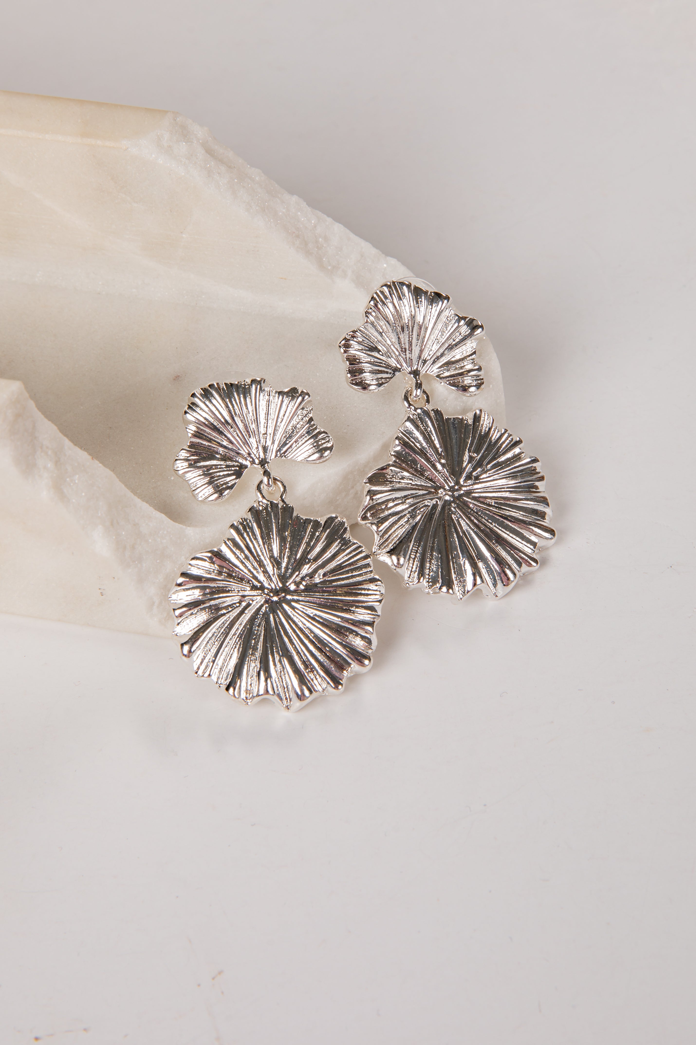 Silver shell-shaped earrings on a light background