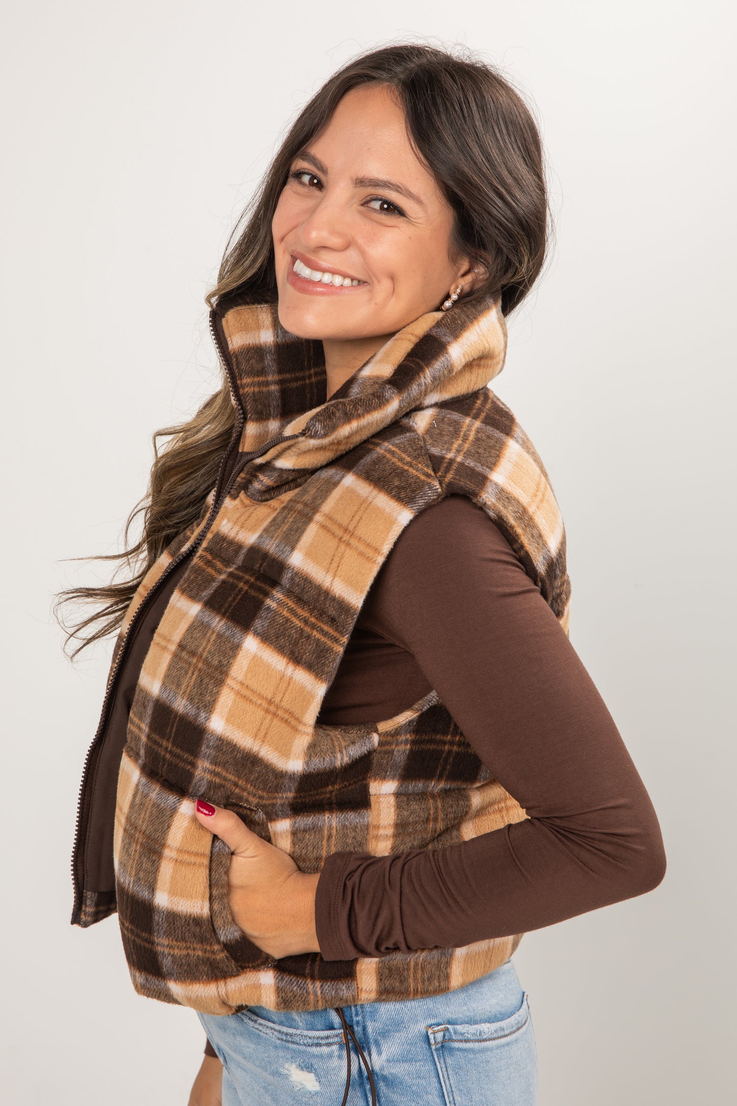 Woman wearing a plaid scarf and vest on a plain background