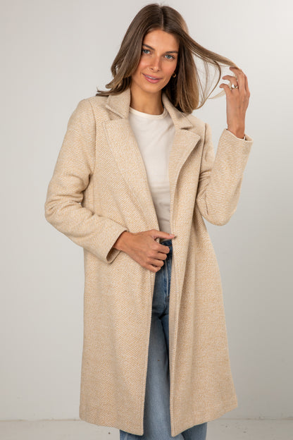 Woman wearing a beige coat with a plain background