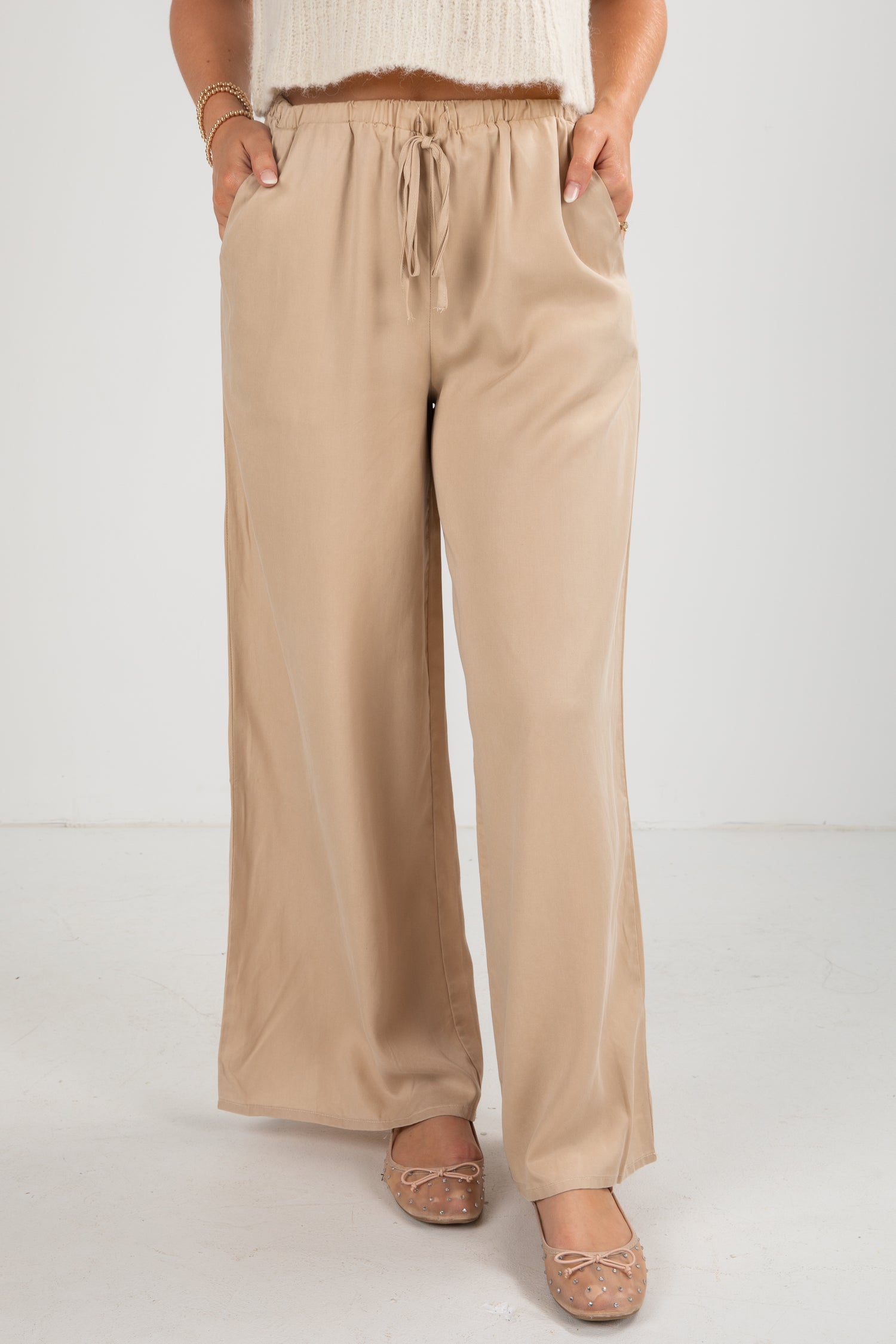 Beige wide-leg pants worn by a person on a white background