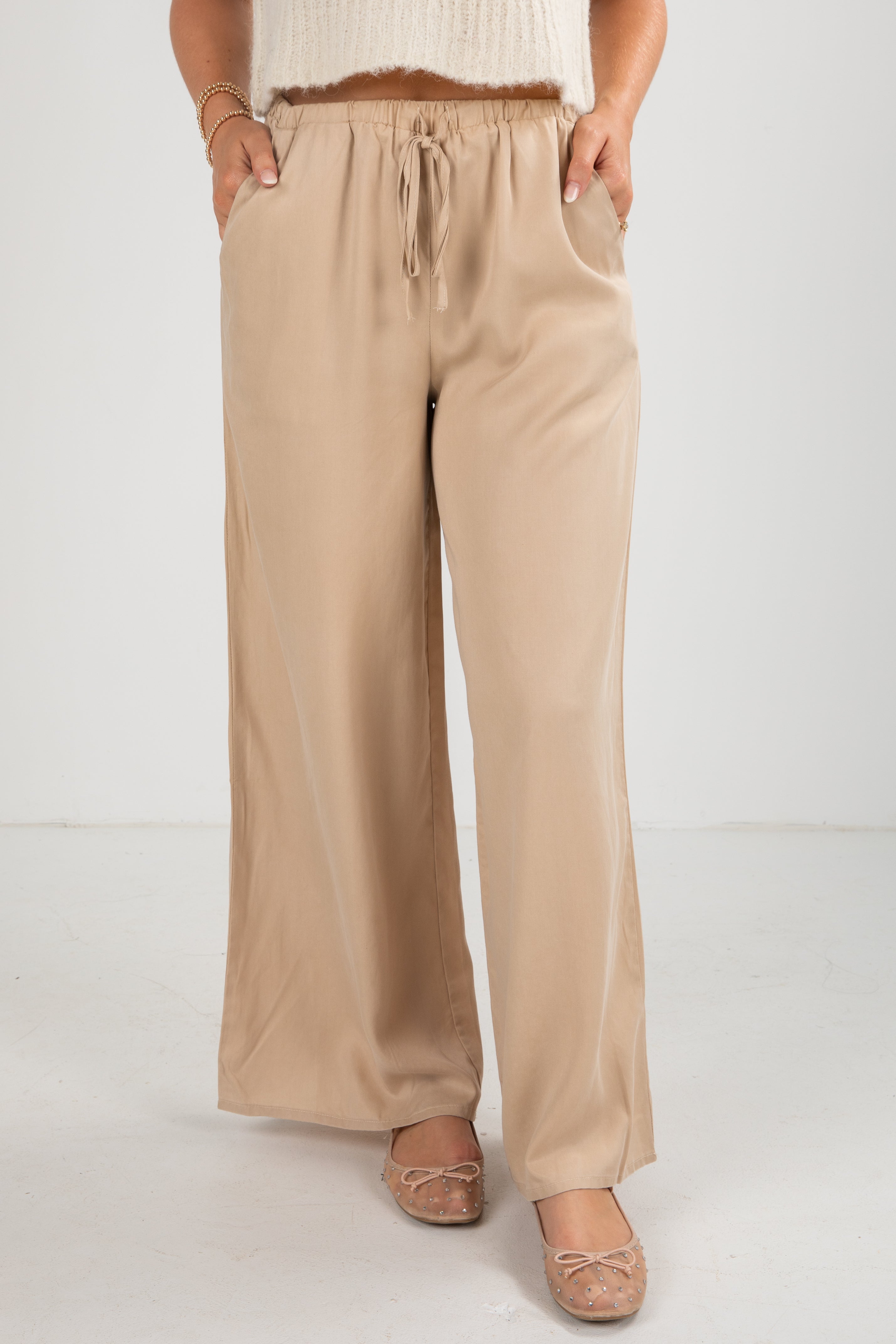 Beige wide-leg pants worn by a person on a white background