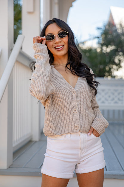 Woman wearing a beige cardigan and white shorts outdoors