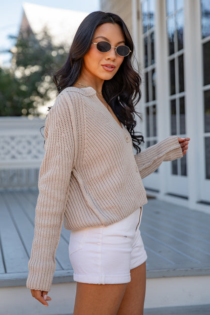 Woman wearing a beige sweater and white shorts outdoors