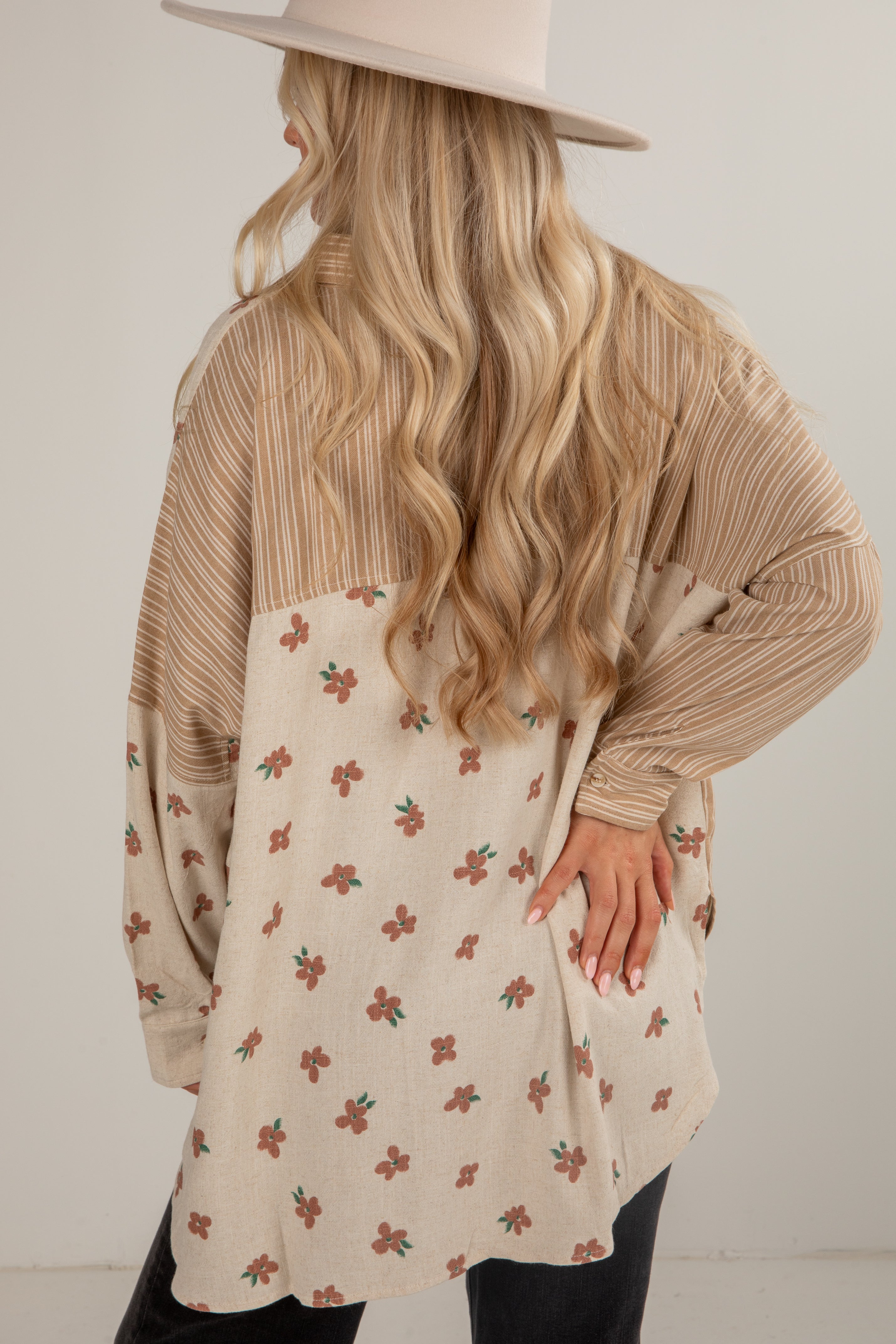 Person wearing a beige sweater over a floral dress with a neutral background