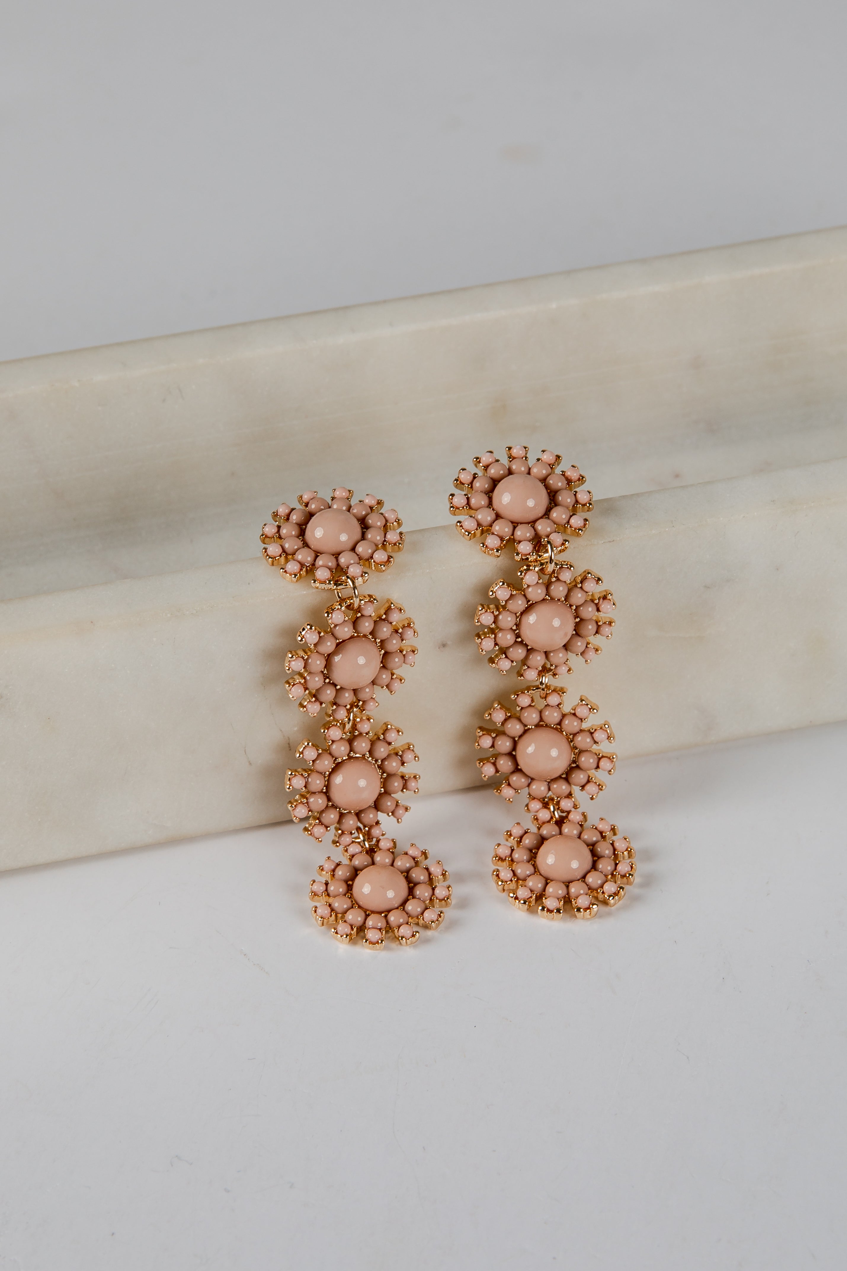 Pair of rose gold and pink floral earrings on a light background