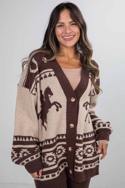 Woman wearing a patterned cardigan with a horse design on a plain background